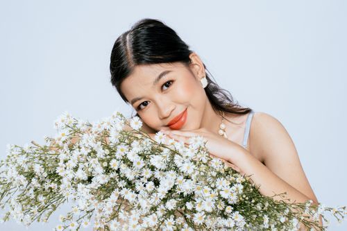 Free Charming portrait of a young woman with a chamomile bouquet, exuding joy and relaxation. Stock Photo