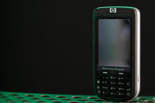 Close-up of a vintage HP iPAQ Business Navigator mobile device on a perforated surface.