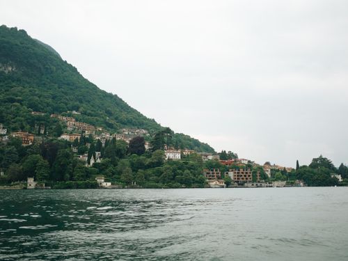 Free Tranquil scene of Lake Como with lush hills and charming waterfront homes under a cloudy sky. Stock Photo
