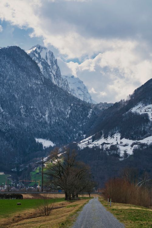 Free Breathtaking view of snow-capped mountains and a serene path in an Alpine valley. Stock Photo