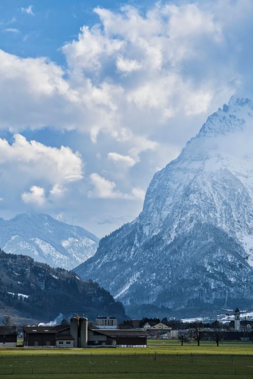 Free Scenic view of towering snow-capped mountains under a bright blue sky with clouds. Stock Photo