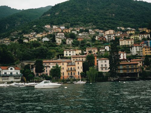 Free Scenic view of charming village by Lake Como in Lombardy, Italy. Boats docked at the waterfront. Stock Photo