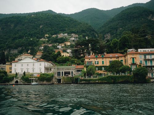 Free Picturesque waterfront with colorful villas at Lake Como, Italy, featuring lush mountains and serene waters. Stock Photo