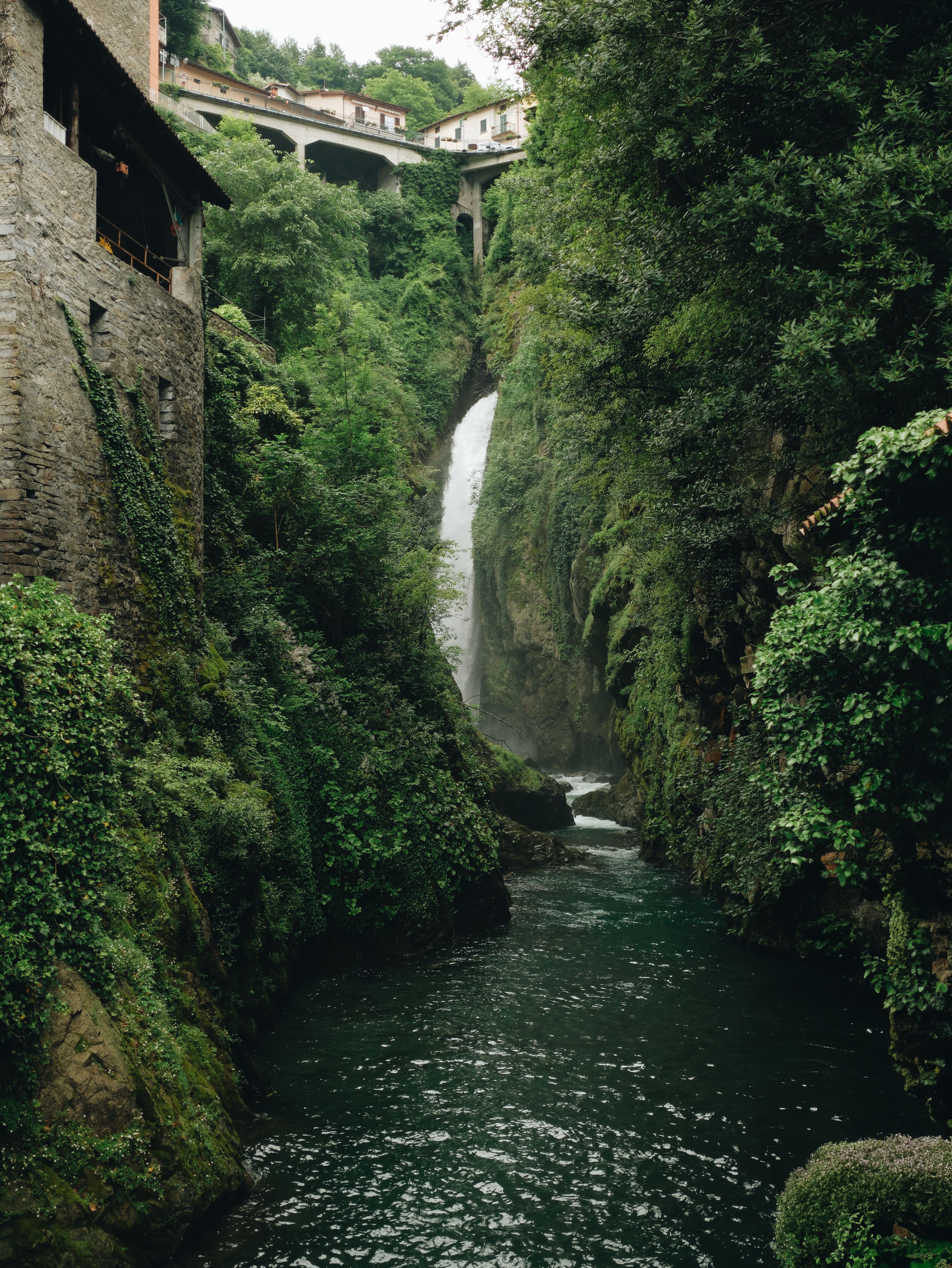 A waterfall in the middle of a river with a bridge · Free Stock Photo