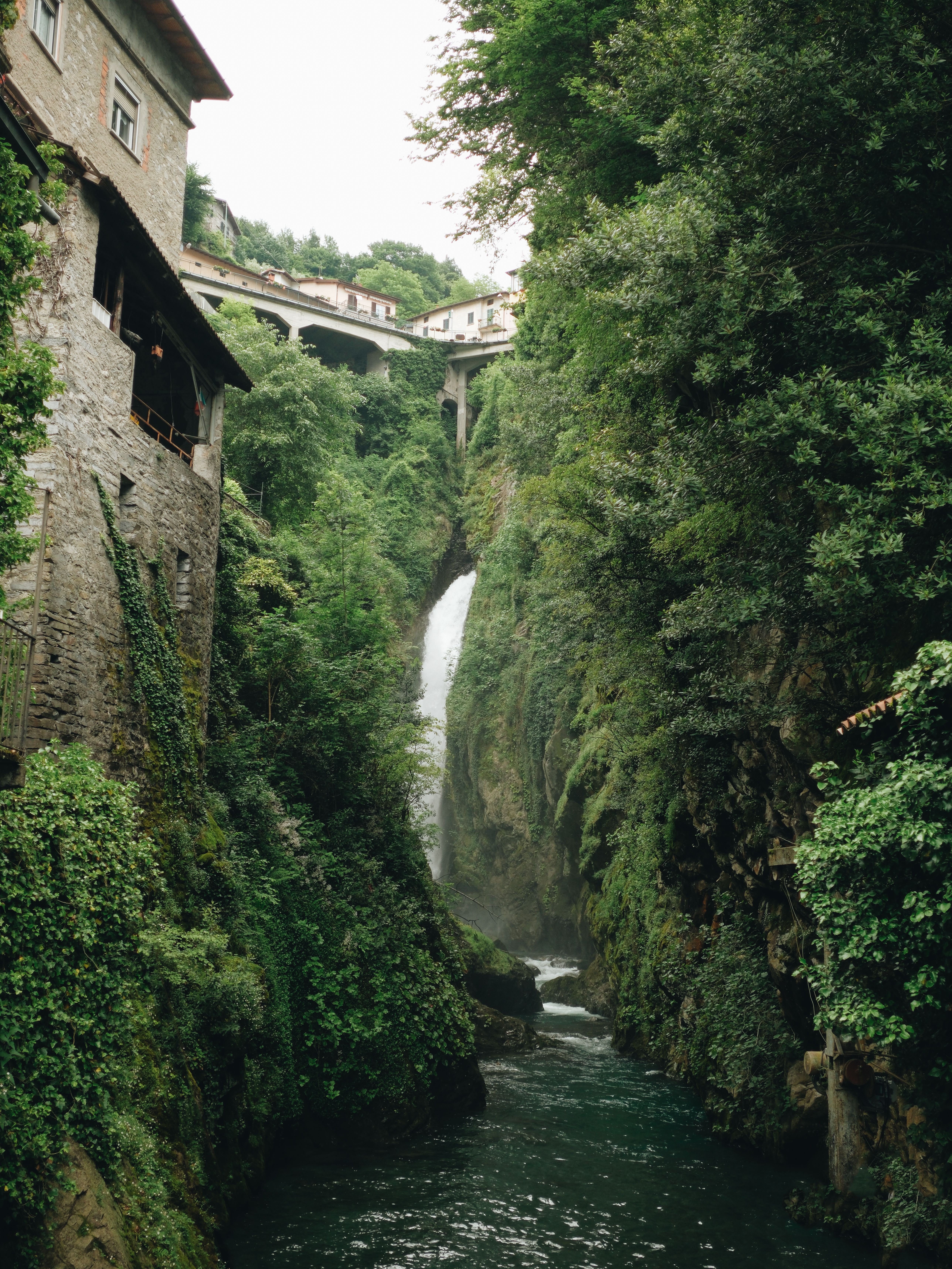 A waterfall in the middle of a river with a bridge · Free Stock Photo
