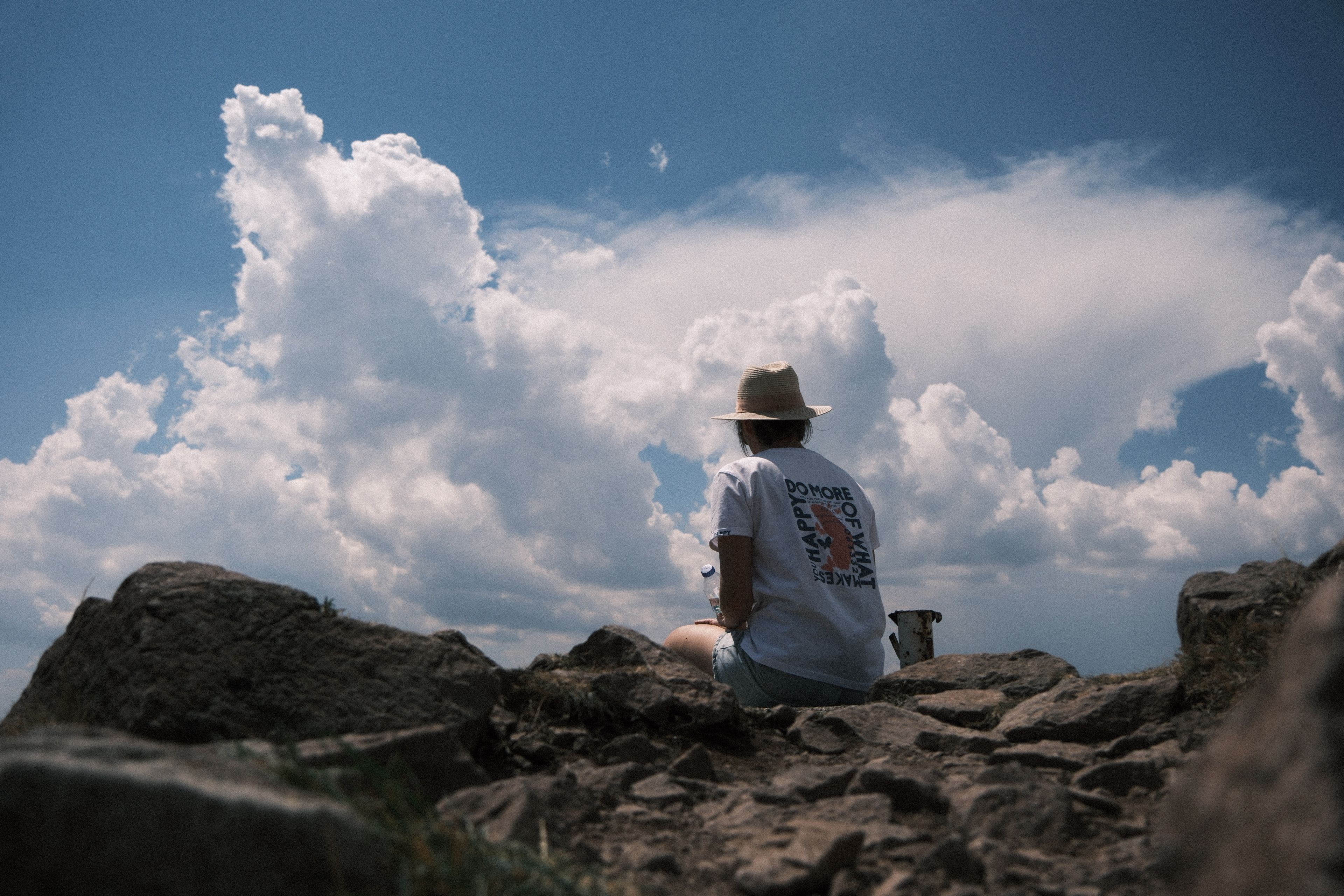 Hiker with Hat Sitting on Rocks on Mountain · Free Stock Photo