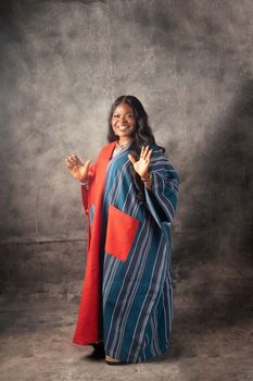 Smiling woman in colorful traditional dress posing with confidence inside a studio setting.