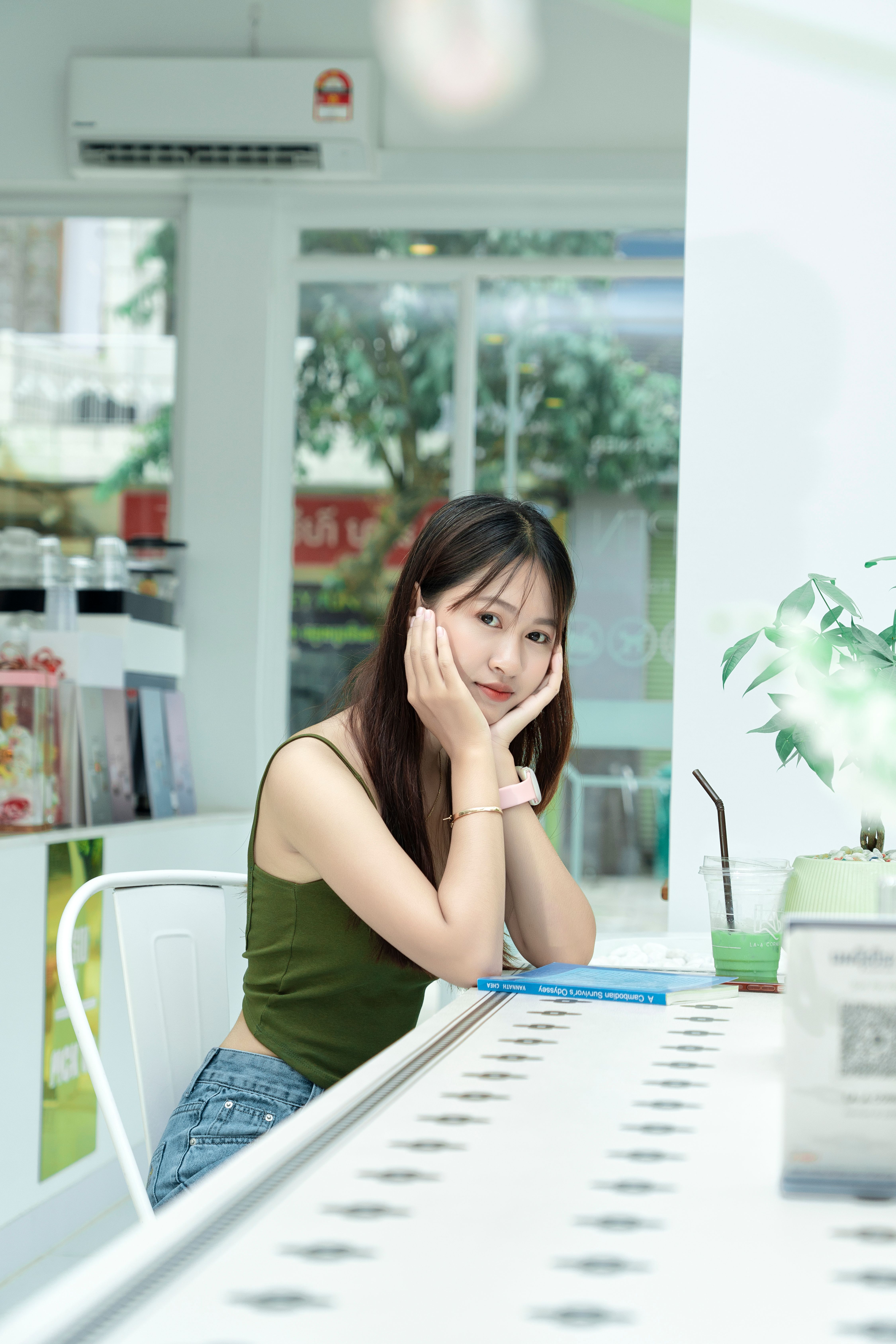 A young woman enjoying a casual moment in a modern indoor cafe setting.