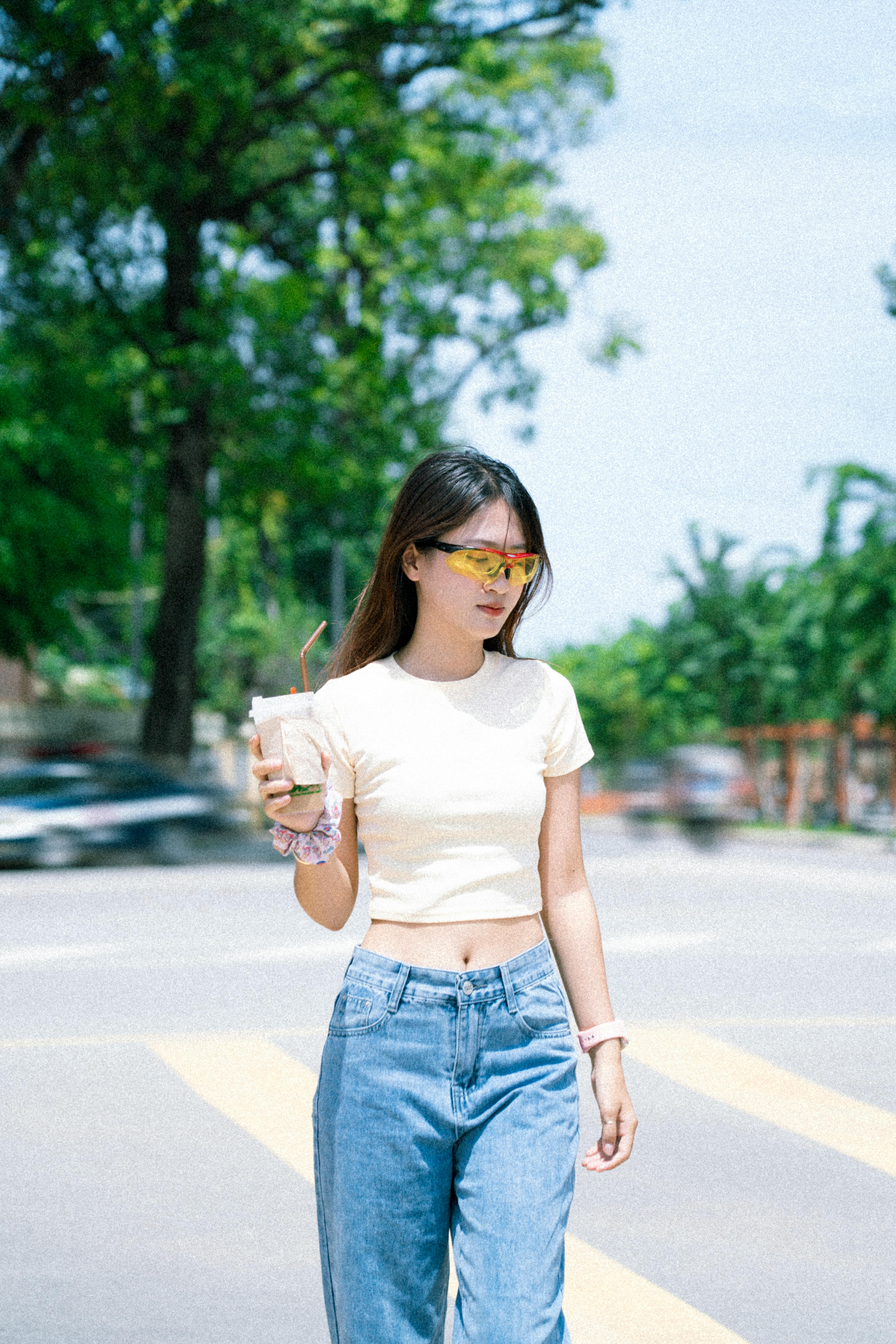 a woman in jeans and a white top is walking across the street