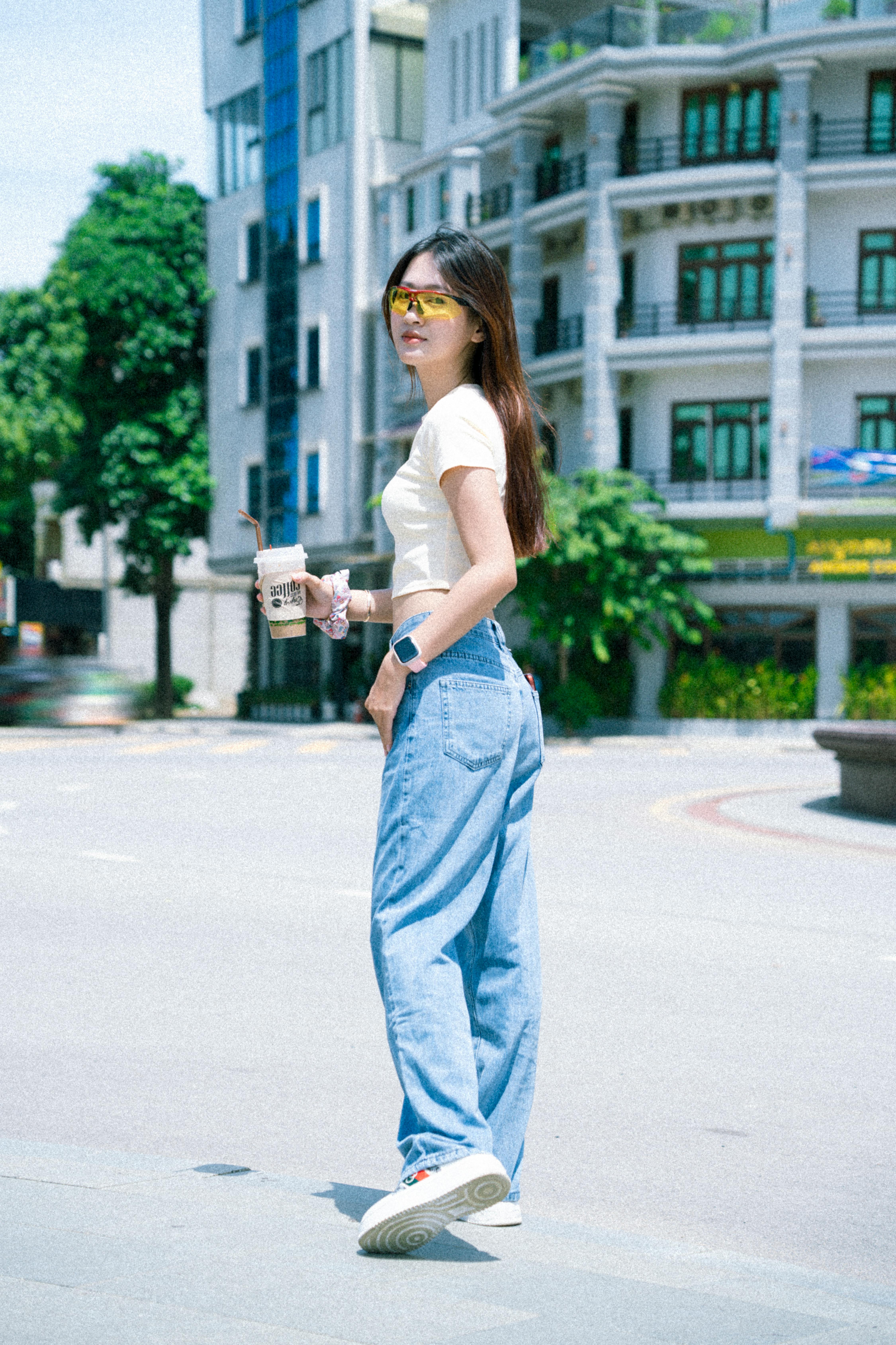 a woman in blue jeans and white shirt standing on the street