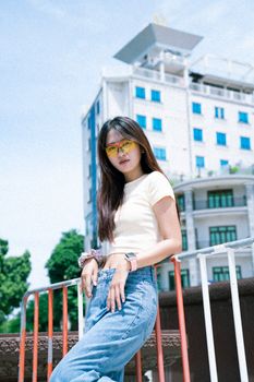 A fashionable young woman poses confidently outdoors with a modern city backdrop.