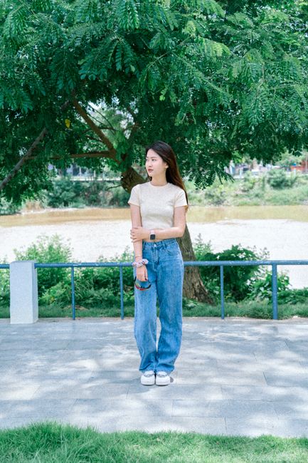 A young woman enjoys a sunny day in a vibrant green park, embodying leisure and joy.
