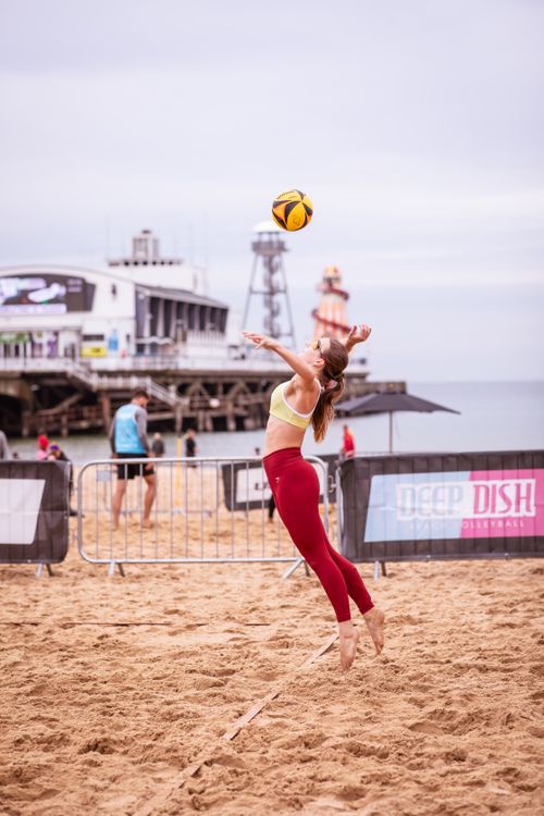 Free Dynamic beach volleyball match in Bournemouth, UK, with a female athlete in action. Stock Photo