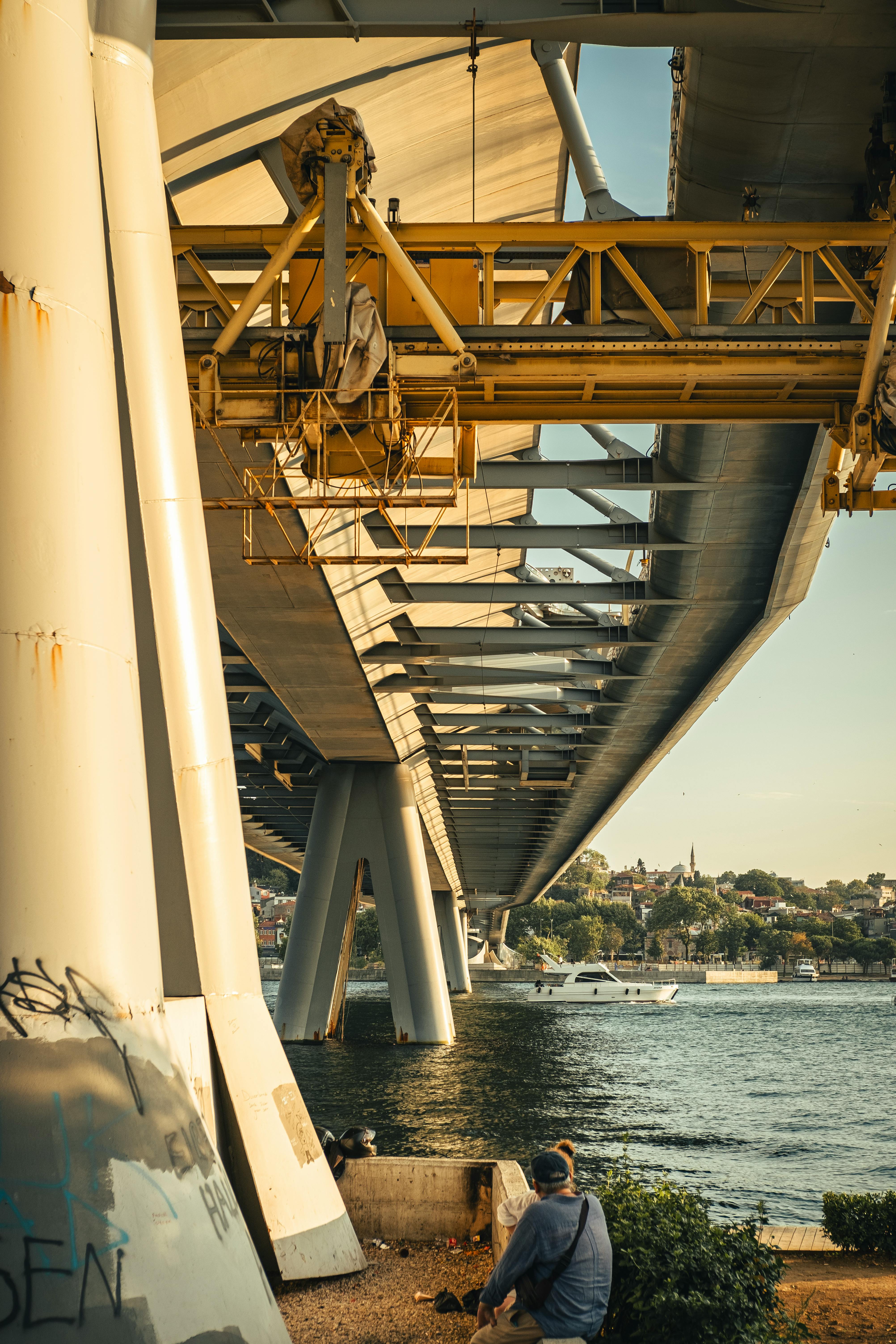 a man sitting on a bench under a bridge