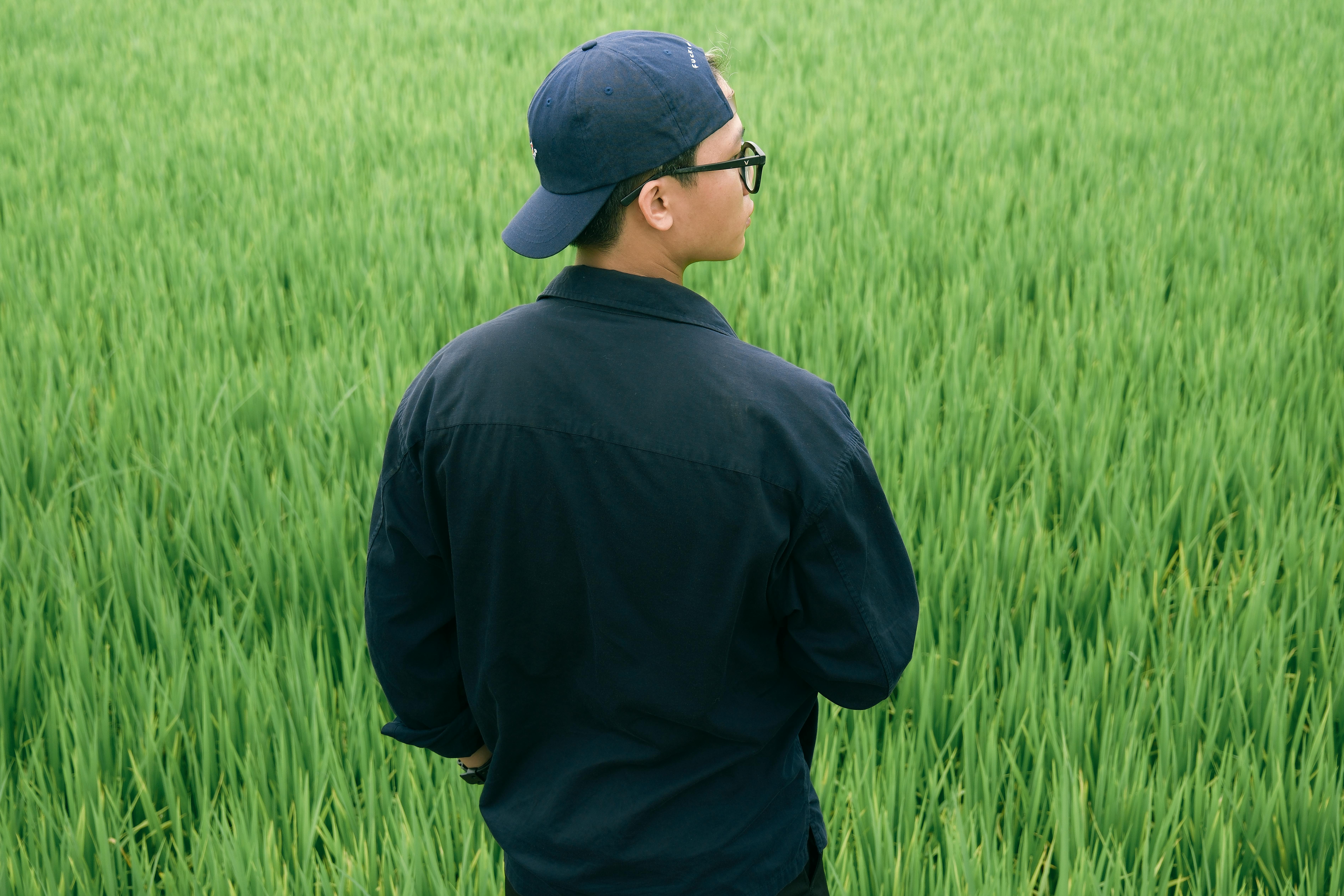 a man in a blue hat and jacket standing in a field