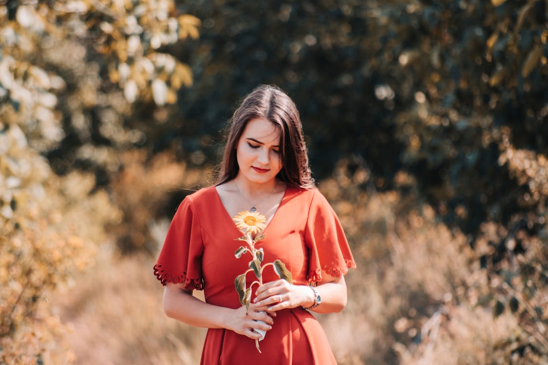 女人穿著紅色的衣服，拿著黃色的花