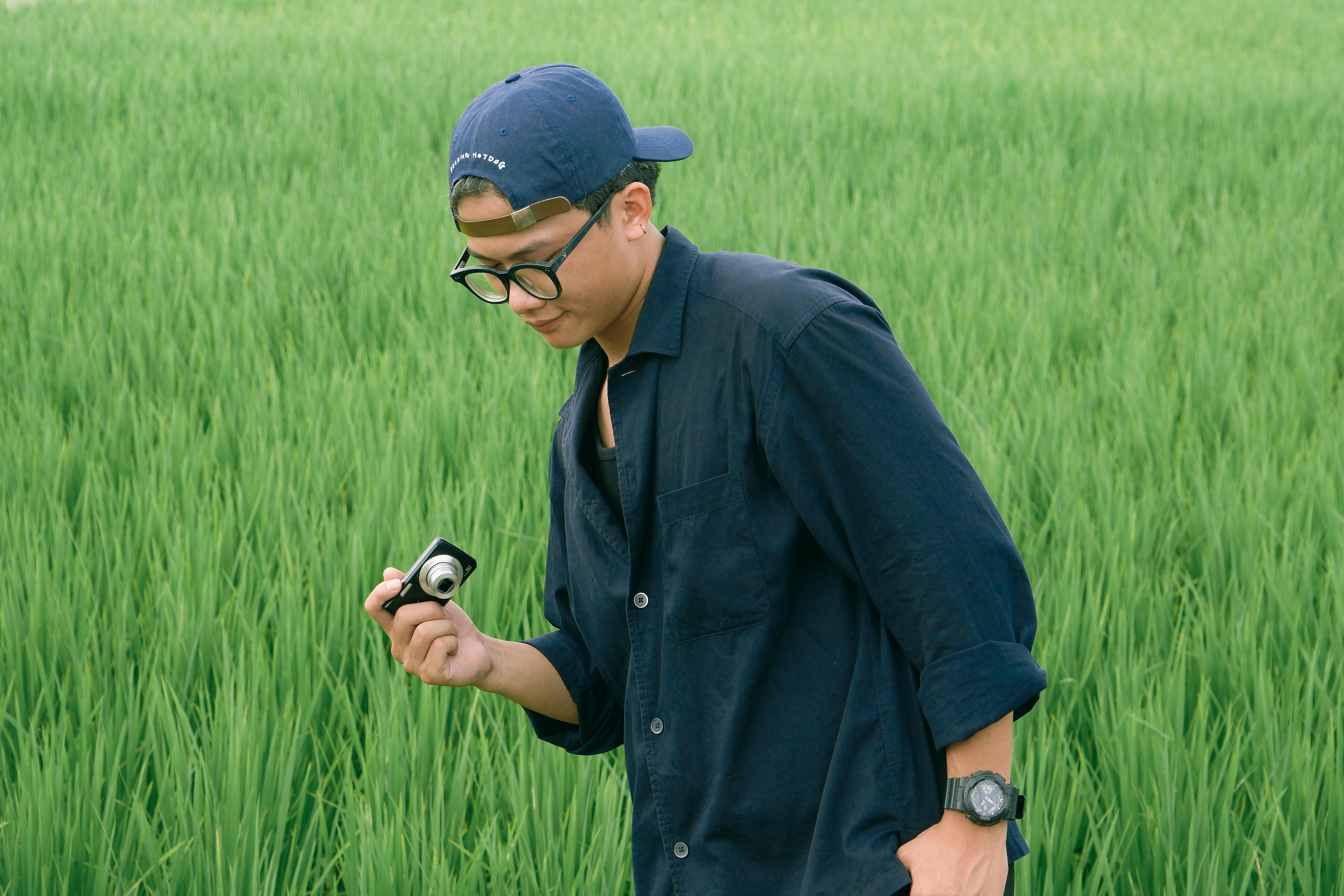 a man in a blue shirt and hat is looking at his phone