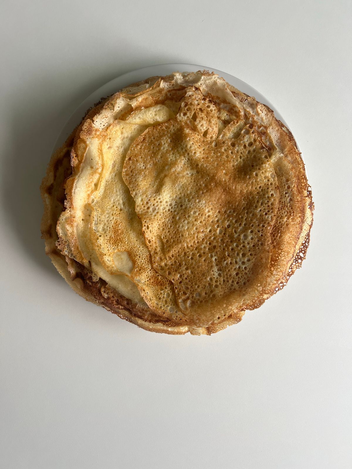 Top view of a neat stack of plain homemade crepes ready for portioning