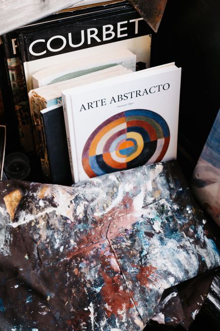 A display of abstract art books with paint-splattered cloth in a creative setting.