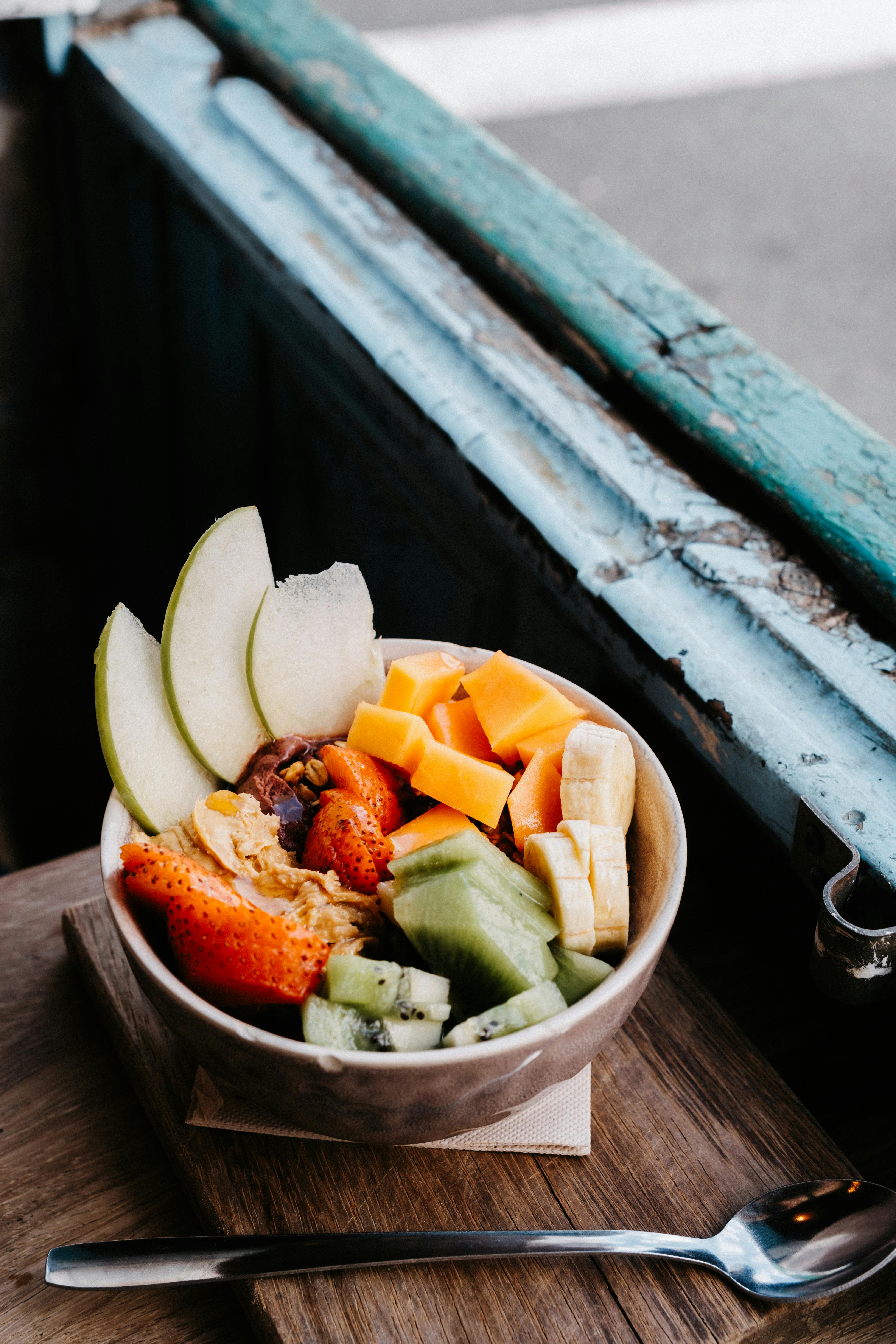 A vibrant bowl of fresh fruit slices including kiwi, banana, and pear, perfect for a healthy snack.