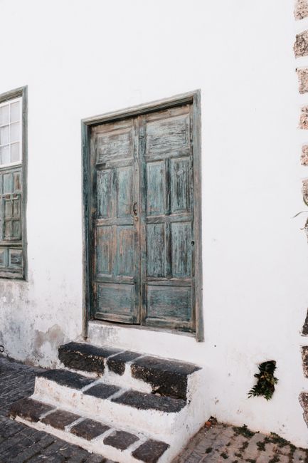 A vintage wooden door and window on a whitewashed wall, exuding rustic charm.