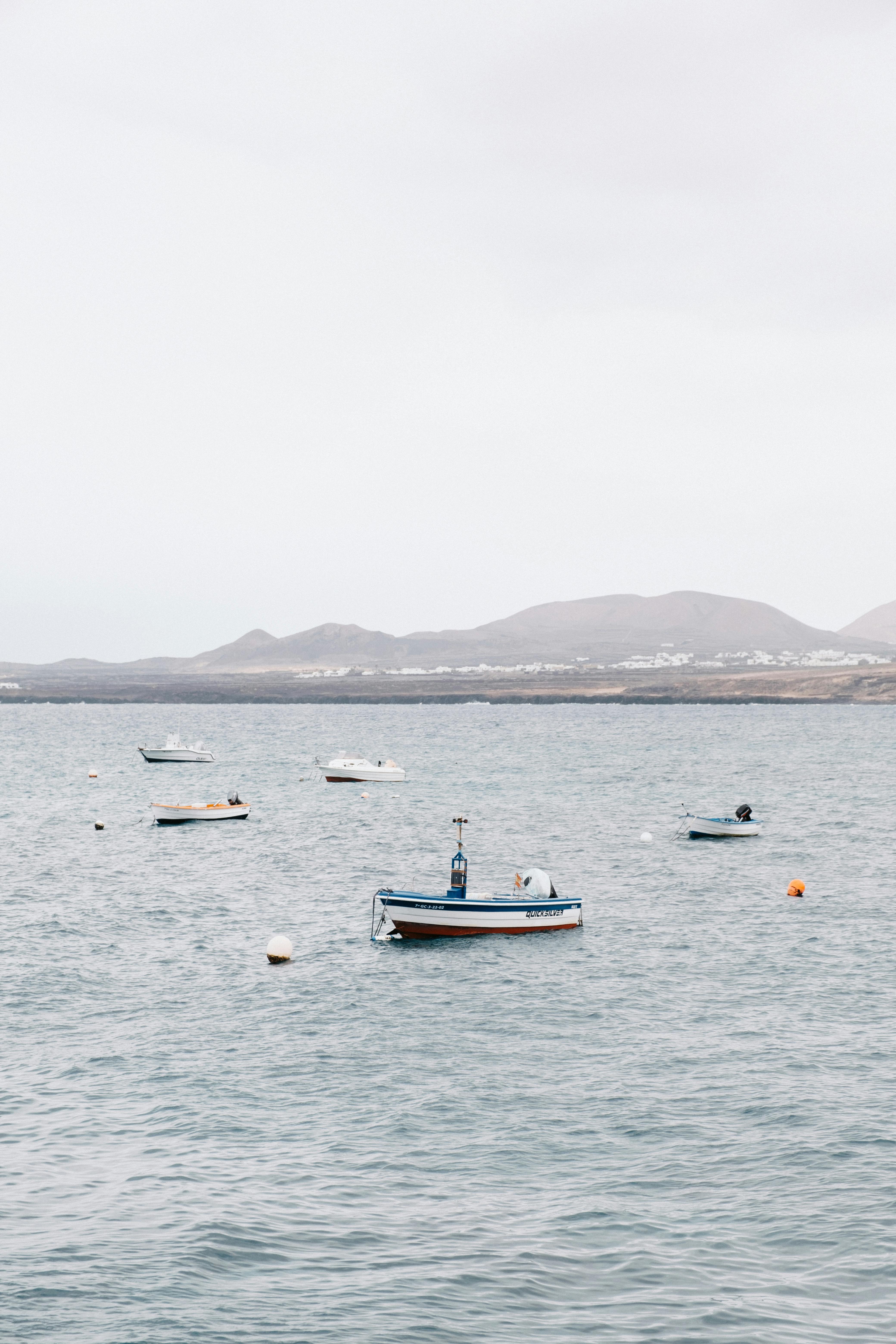 Tranquil boats float on the calm sea against a distant mountainous backdrop, ideal for travel concepts.