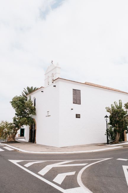 A serene white church with rustic charm on a clear summer day, captured at a street intersection.