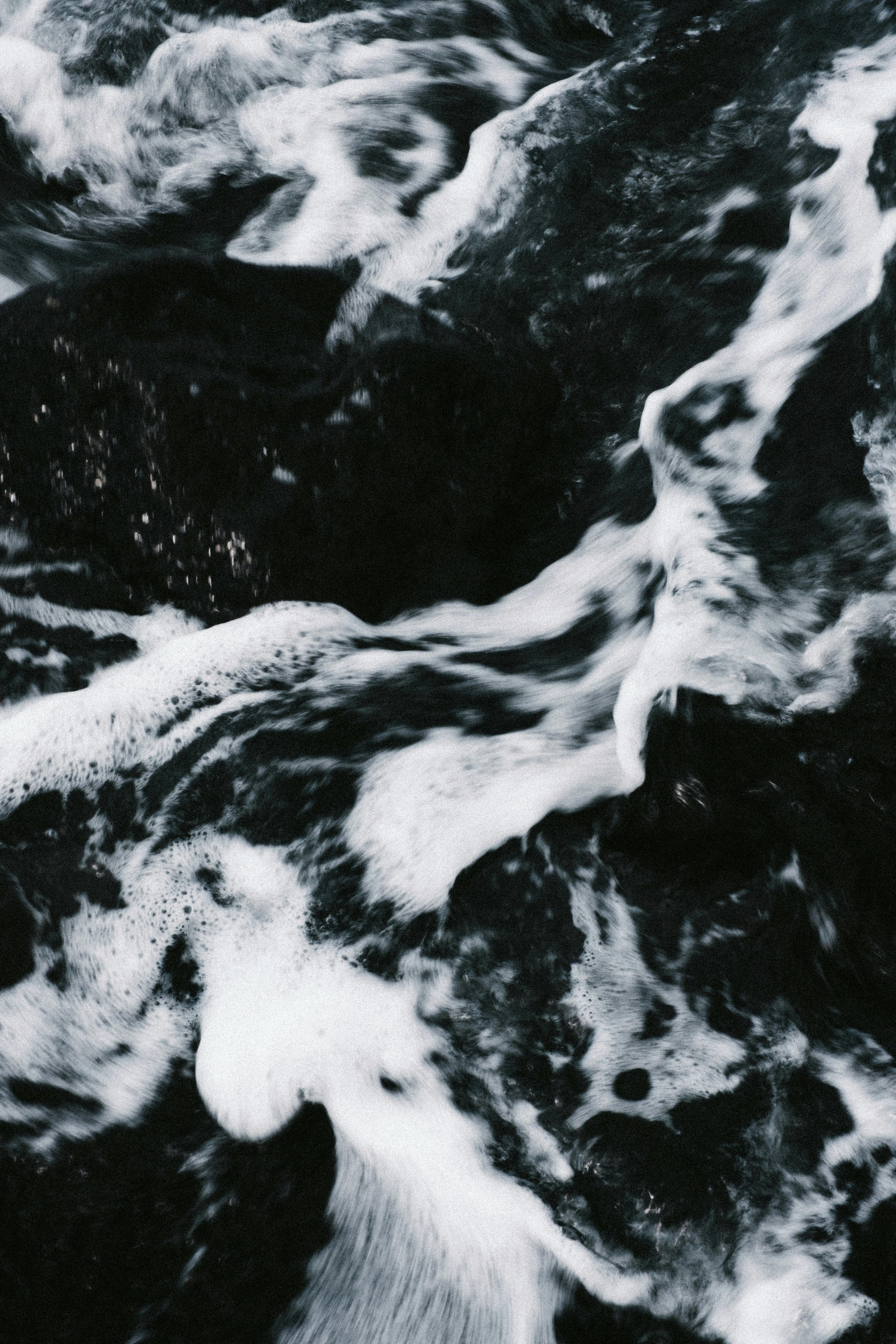 Captivating image of icy water flowing over dark rocks, showcasing the beauty of nature's motion.