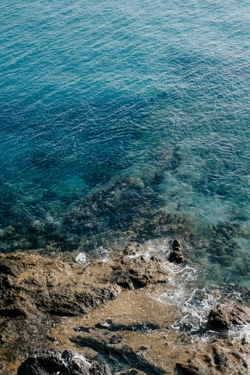 Free A stunning view of turquoise waters meeting rugged rocks, exemplifying natural coastal beauty. Stock Photo