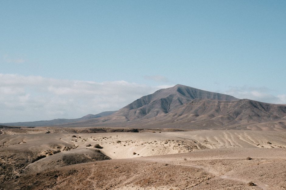 A serene desert landscape with mountain under a clear blue sky, evoking adventure.