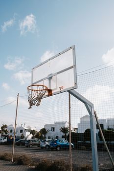 A basketball hoop stands tall in an urban outdoor setting with clear blue skies.