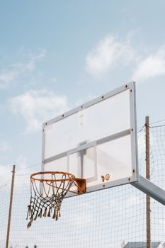 A clear basketball hoop with net set outdoors under a blue sky, perfect for sports or recreation themes.