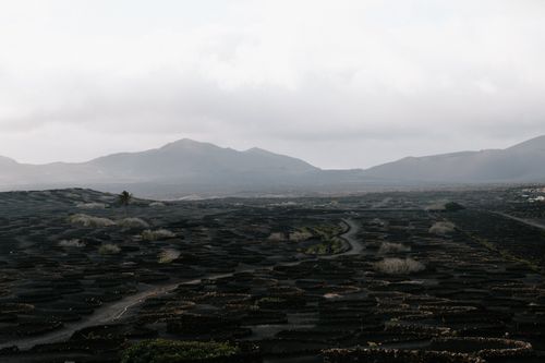 Free A serene volcanic landscape under cloudy skies with distant mountain views. Stock Photo