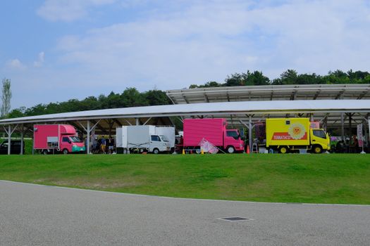 Colorful food trucks lined up in Ghibli Park, Nagoya, offering diverse culinary delights.