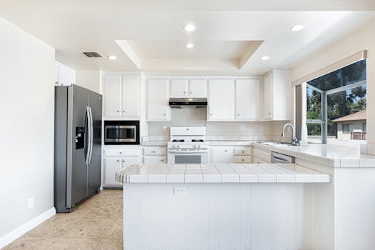 Spacious white kitchen featuring stainless steel appliances and contemporary design for comfortable living.
