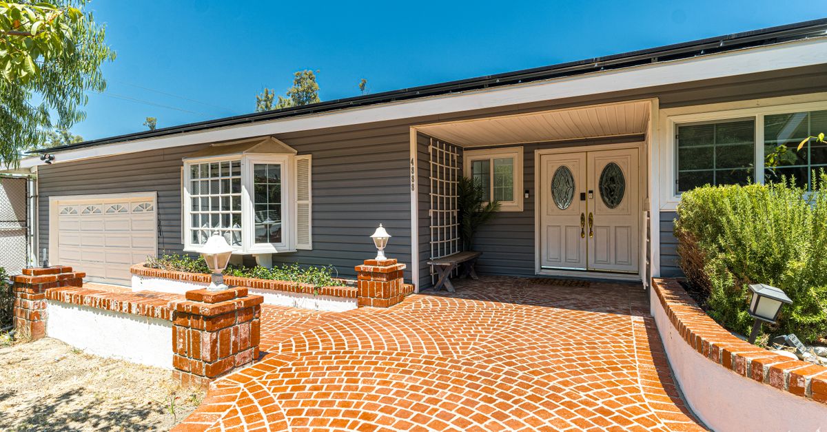 Beautiful suburban house featuring a stylish brick driveway and spacious patio.