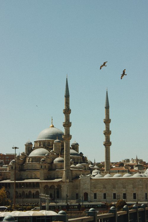 Free Beautiful mosque with towering minarets soaring into a clear blue sky, highlighted by soaring birds. Stock Photo