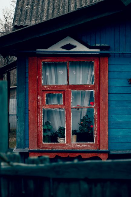 Charming red-framed window of an old house in Minsk, Belarus, surrounded by countryside charm.
