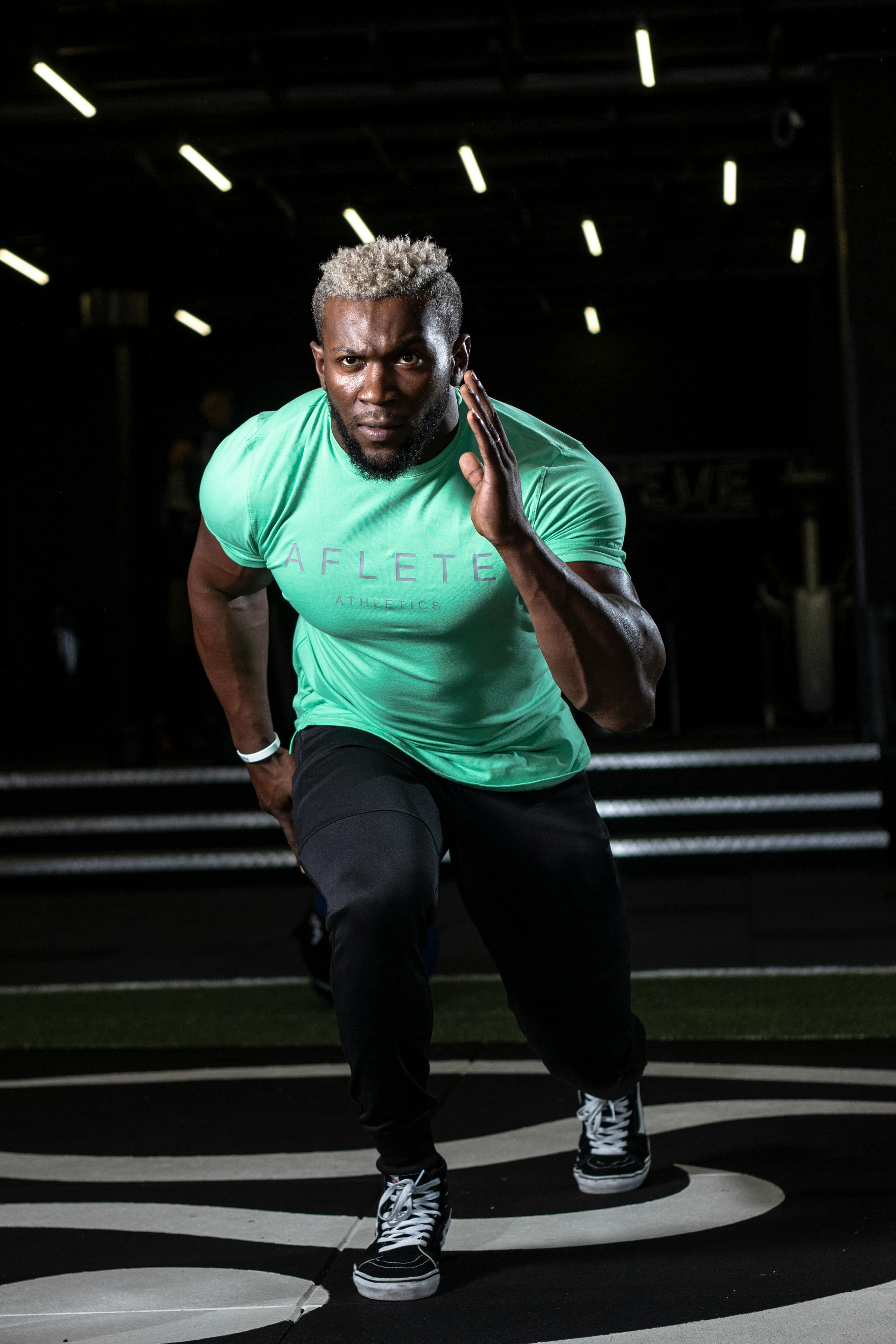 运动员穿着绿衬衫在室内冲刺，展现了力量和决心