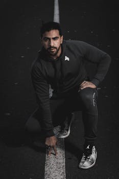 一名年轻人自信地蹲在城市道路上，散发着都市风格与决心