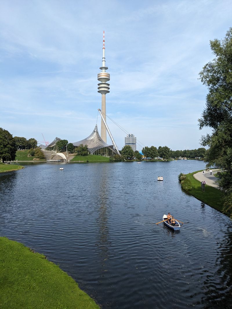 Olympiaturm tower and Olympic stadium roof across the Olympiapark lake in Munich