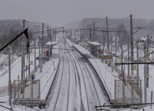 Free Deserted snowy railway station during winter with multiple tracks and overhead wires, creating an industrial scene. Stock Photo
