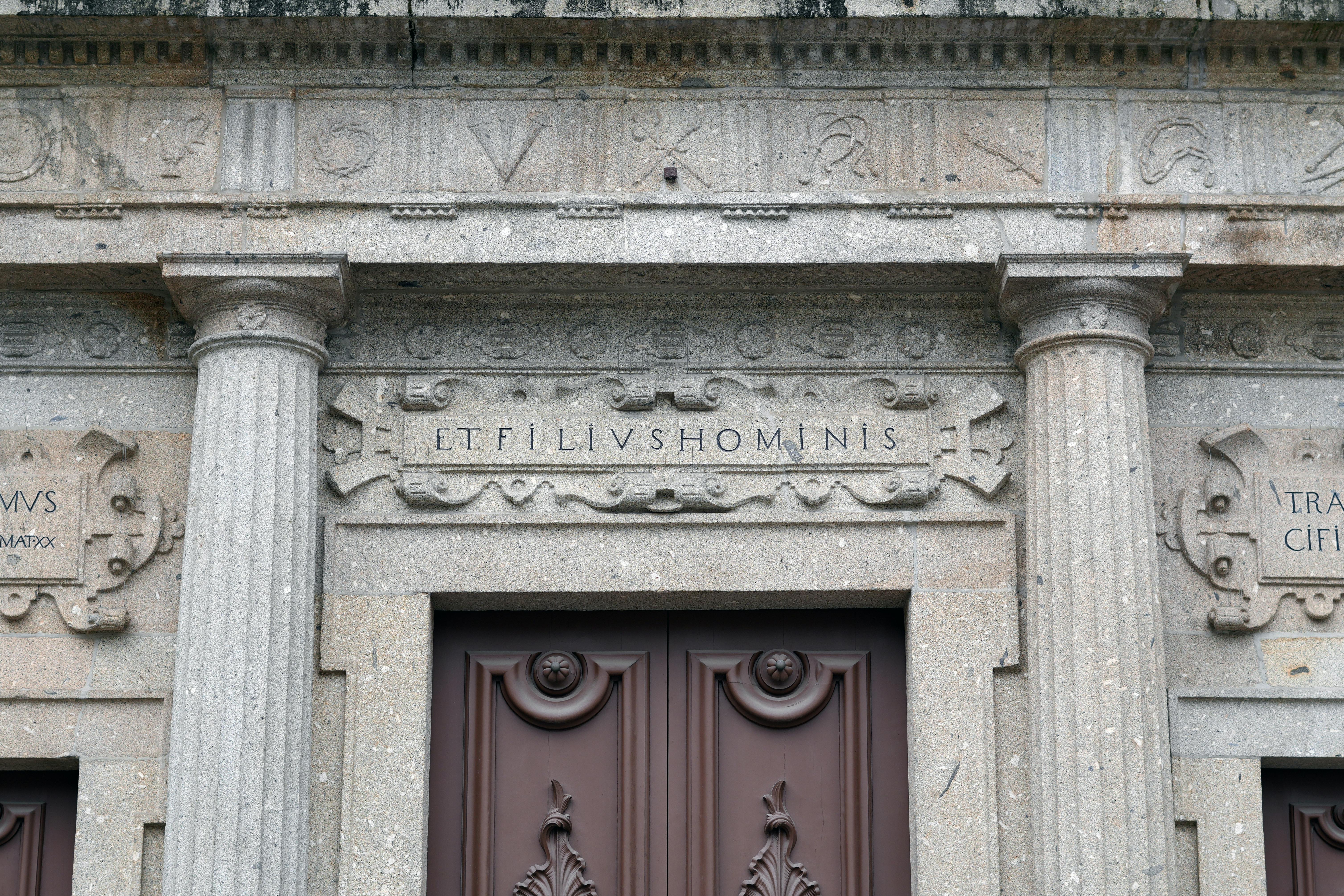 Close-up of a classical stone facade with Latin inscriptions and detailed columns.
