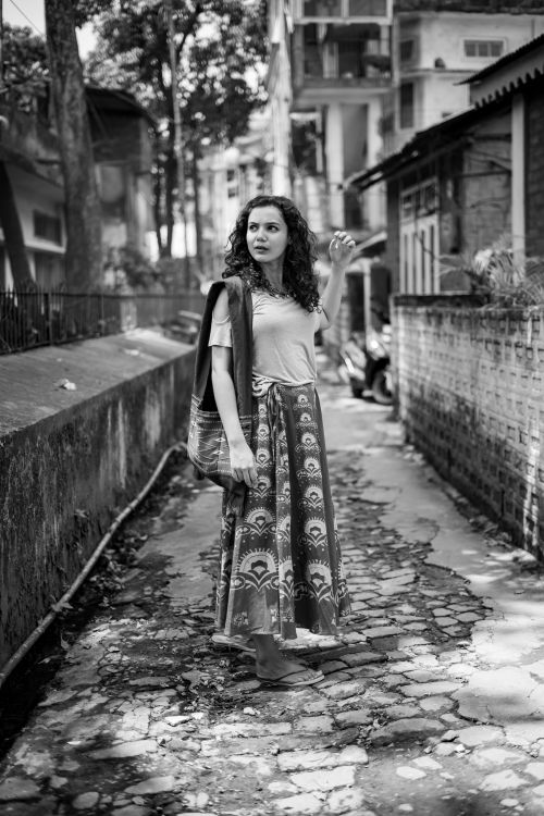 Free Black and white photo of a young woman with curly hair walking in a Guwahati alley. Stock Photo