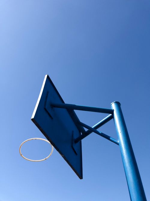 Free Low-angle shot of a blue basketball hoop against a clear blue sky, ideal for sports themes. Stock Photo