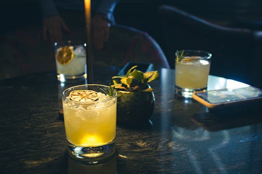 Chic cocktails with lemon garnish on a stylish table in a dimly lit Kilkenny bar, perfect for nightlife vibes.