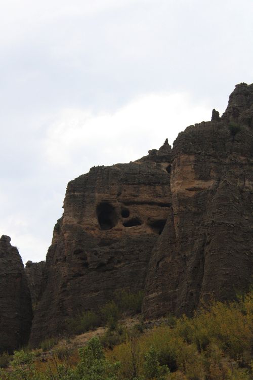 Free A stunning view of rocky cliffs with natural caves under a cloudy sky. Stock Photo