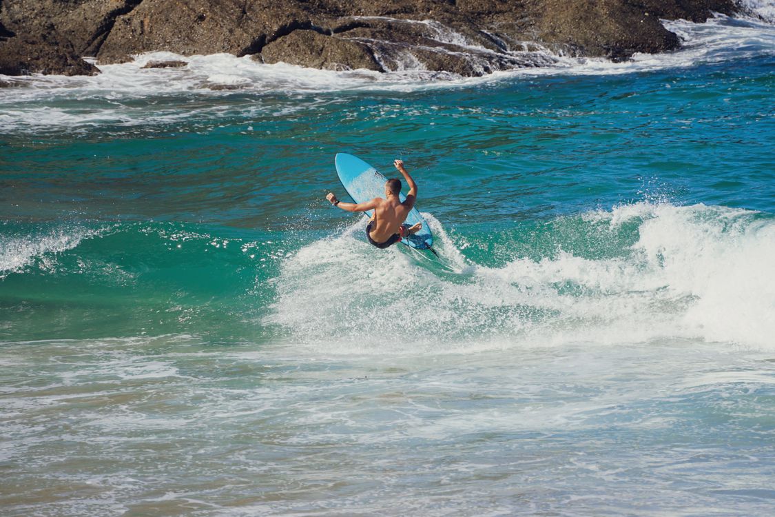 The Rocking Surfer Man Surfing by Rocky Shore · Free Stock Photo