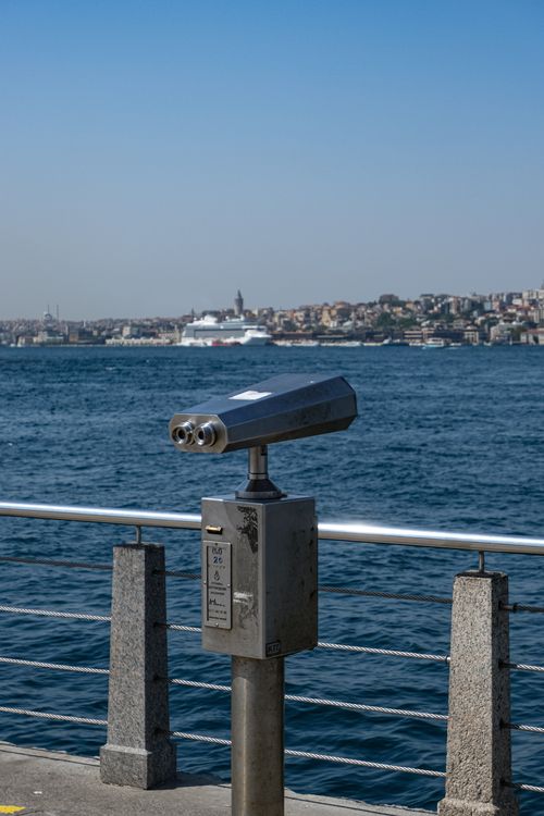 Free Public binoculars viewing a scenic harbor with a distant city skyline and cruise ship. Stock Photo