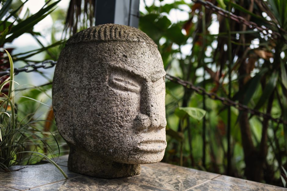 A detailed stone sculpture set in a lush outdoor garden in Ciudad Colón, Costa Rica.